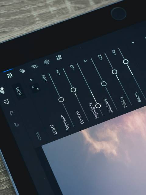 A close-up view of a tablet displaying adjustable settings on a control panel screen with a wooden background.