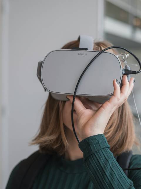 A woman is wearing a virtual reality headset in a modern office environment.