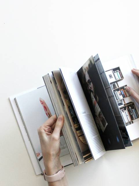 A person browsing through an open photo album with various images.