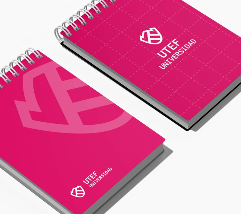 Two pink notebooks with wire bindings displayed diagonally, featuring the logo and name of UTEF Universidad on the covers.