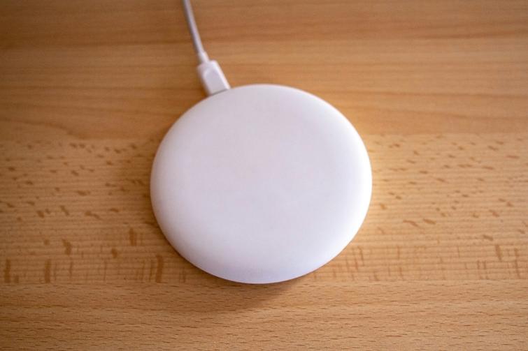 A white, round device with a cable on a wooden surface.