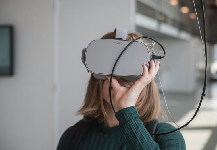A woman is wearing a virtual reality headset in a modern office environment.